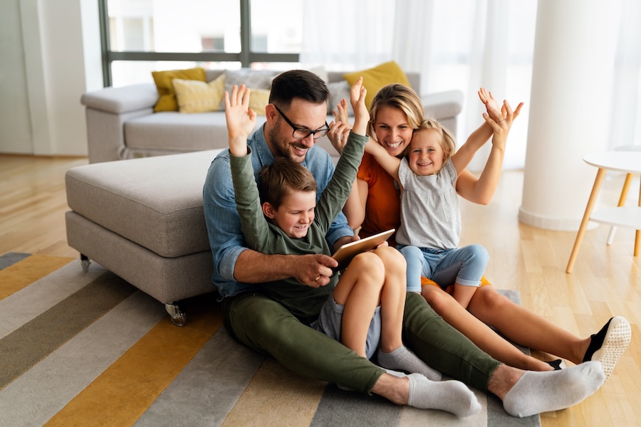 Rodzina korzystająca z tabletu do sterowania systemem smart home w jasnym salonie